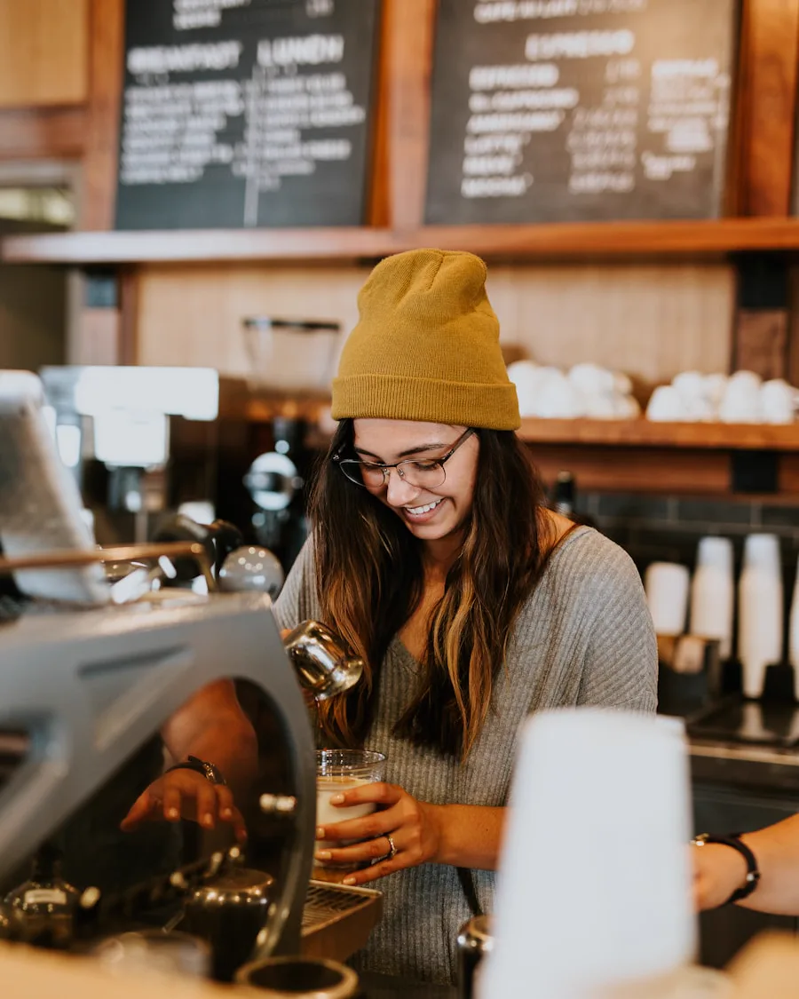 Smiling barista pouring a drink behind the counter of a warm coffeehouse