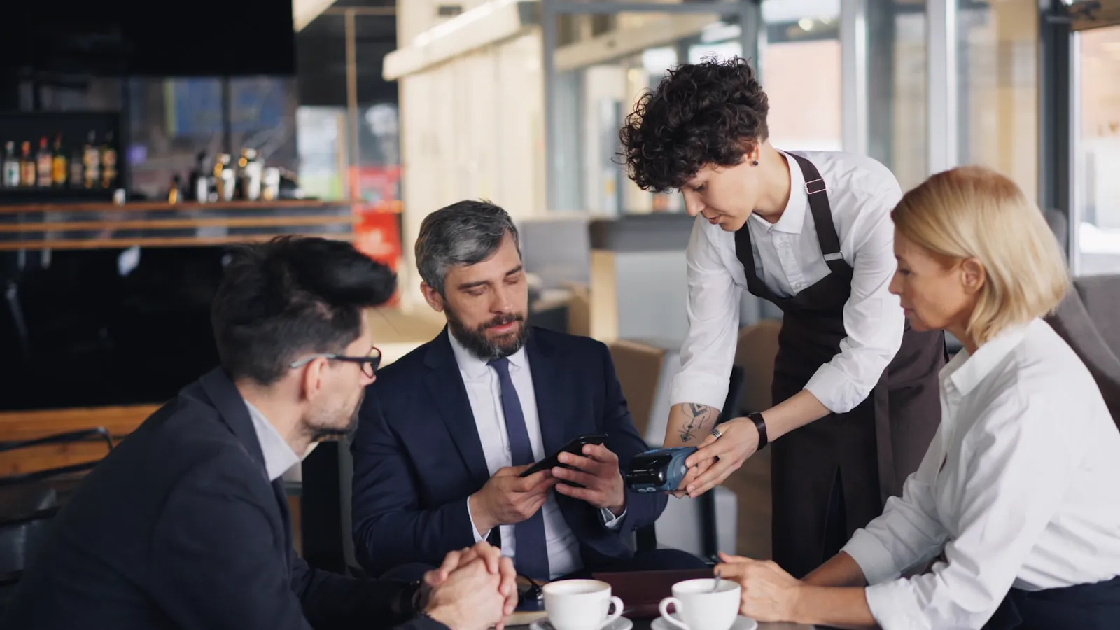 Server taking a payment at a table of business diners